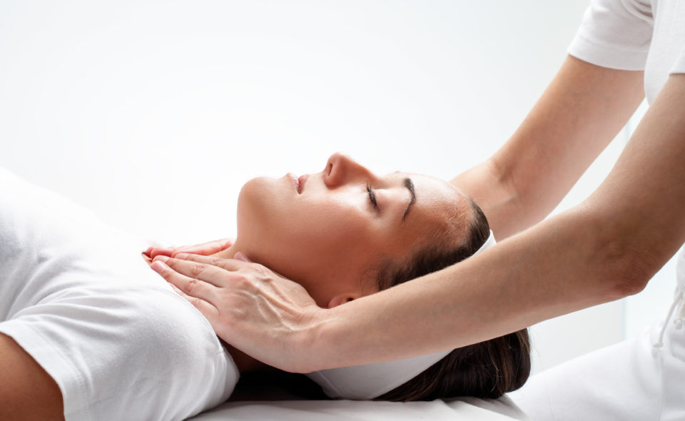 Close up portrait of young woman at reiki session.Therapist touching woman’s neck wit hands.